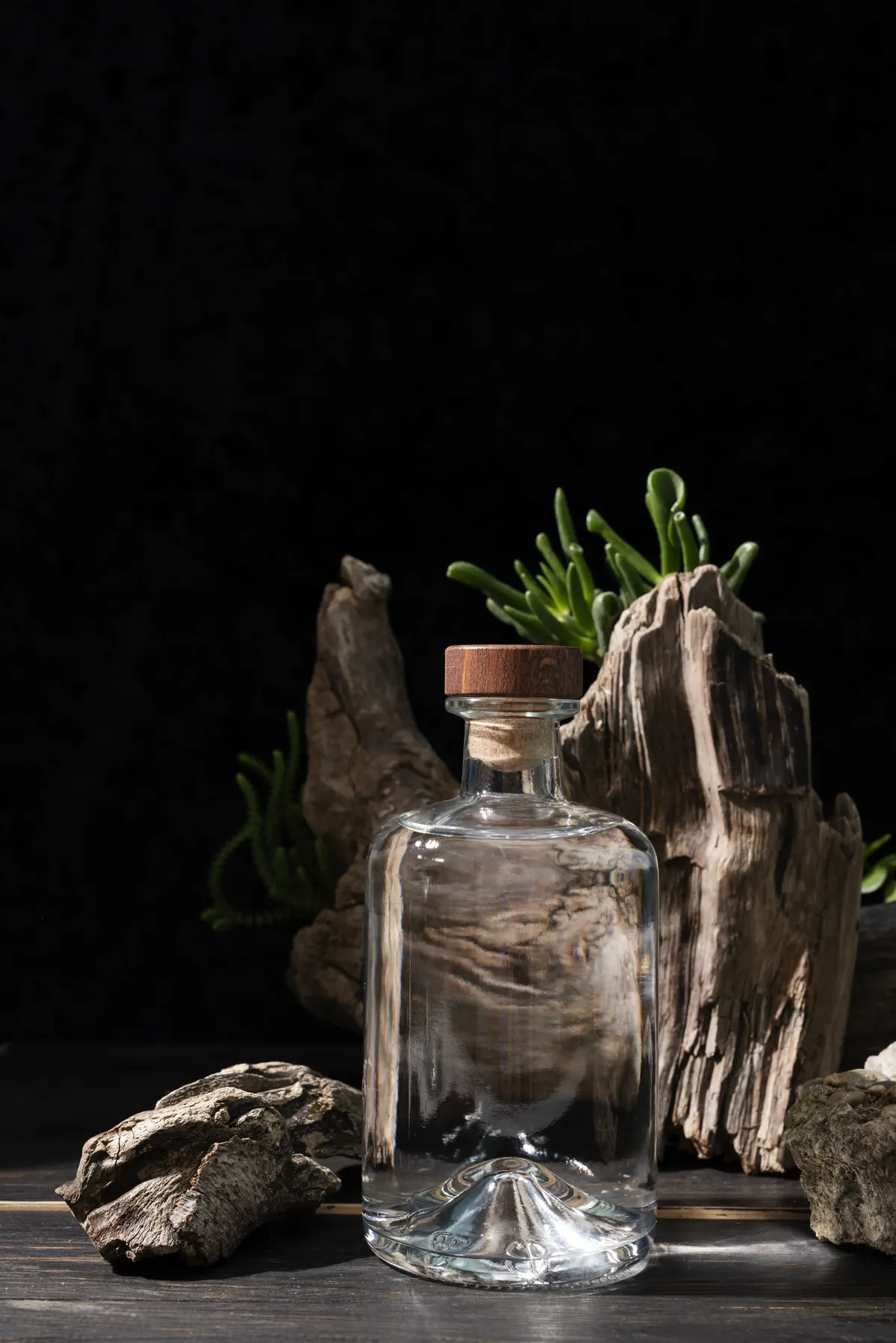 Perfume bottle set against weathered agarwood in low light