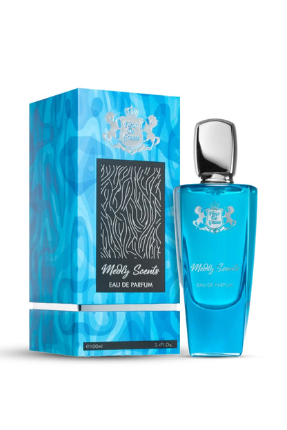 A bottle of FLEUR DE GRASSE MEDLEY SCENTS EAU DE PARFUM 100 ML fragrance with its packaging box. The bottle is transparent with a blue liquid inside and the packaging has a blue and black design.